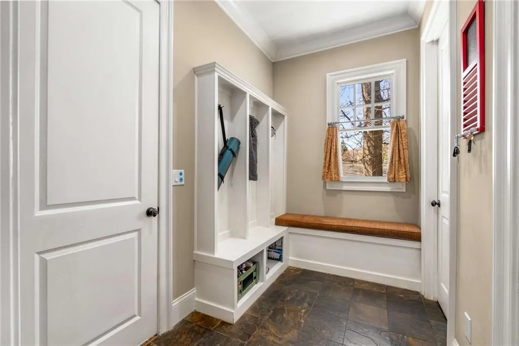 Mudroom with ornamental molding, stone finish floor, and baseboards