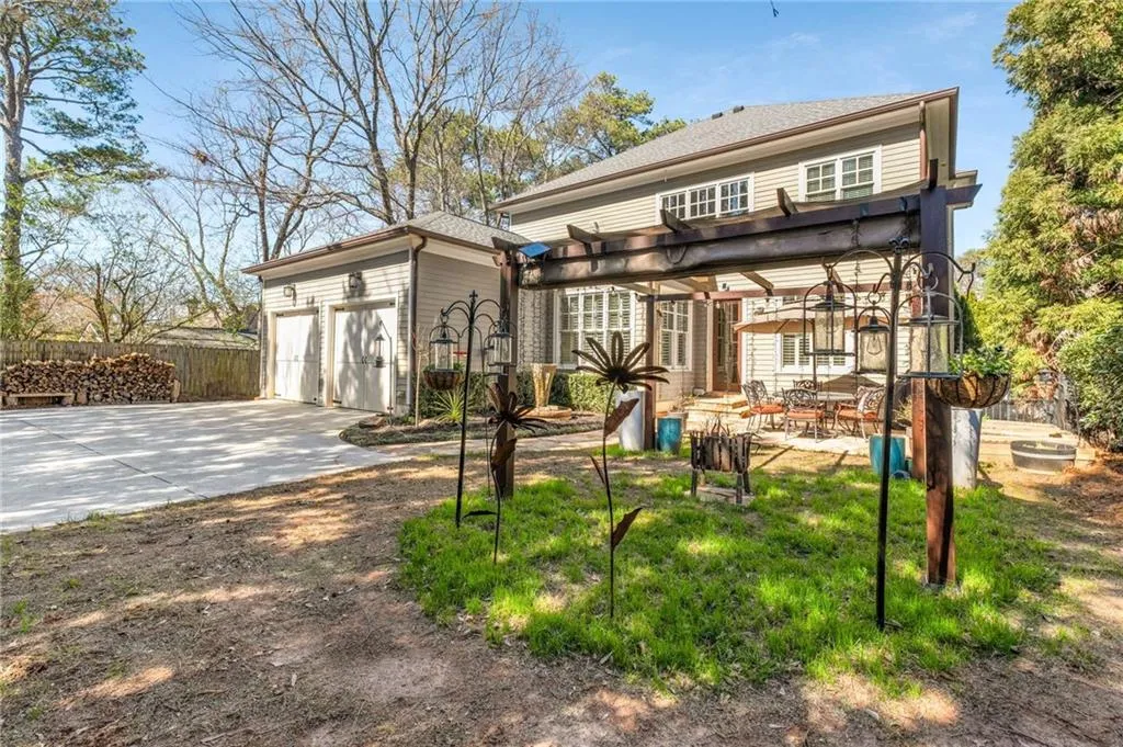 Back of property with driveway, a patio, an attached garage, fence, and a pergola