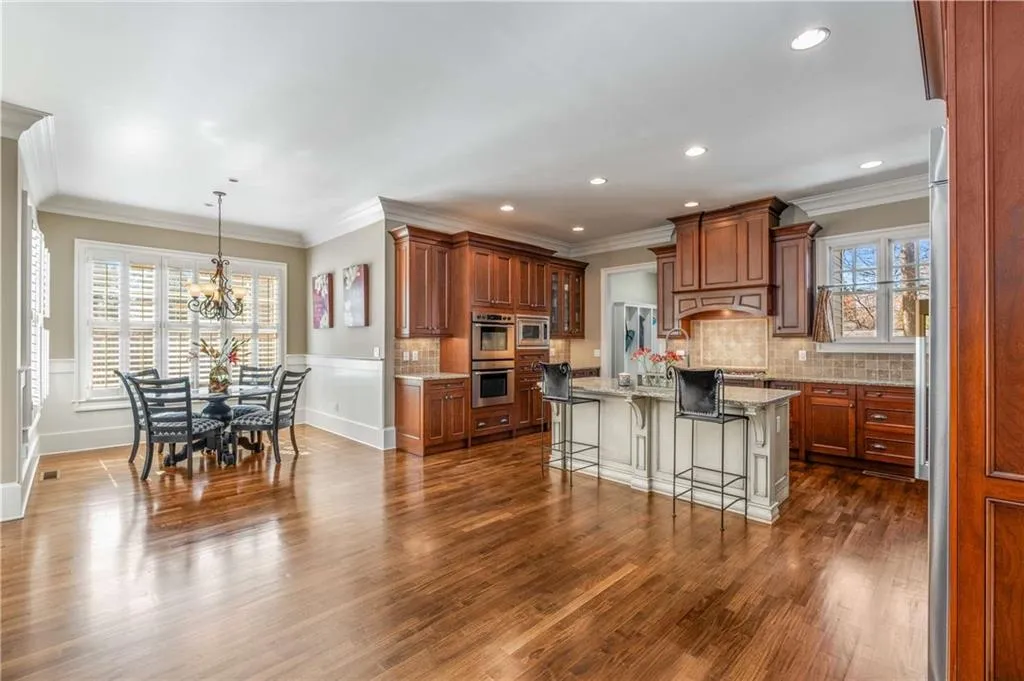 Kitchen featuring dark wood-style floors, brown cabinetry, backsplash, and a kitchen breakfast bar