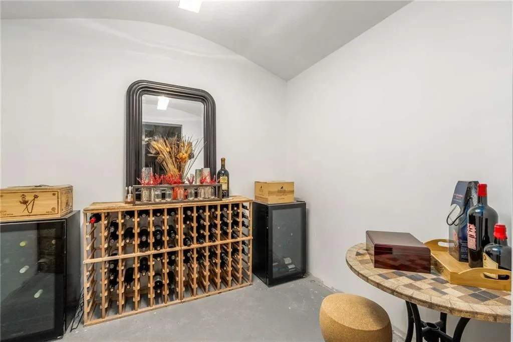 Wine room featuring concrete flooring, wine cooler, and vaulted ceiling