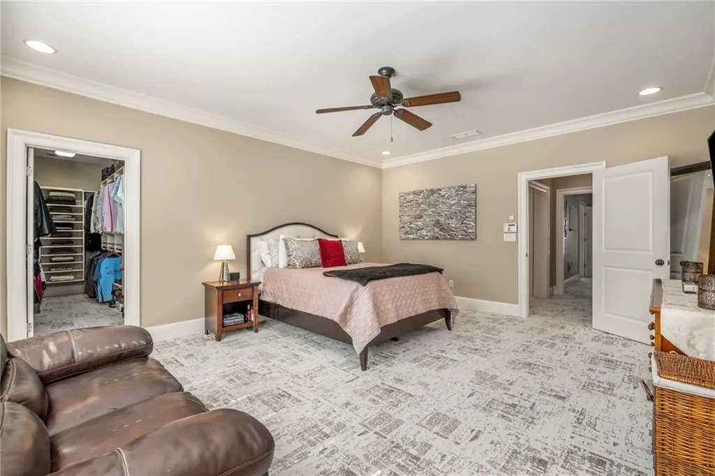 Bedroom with light carpet, a spacious closet, baseboards, and ornamental molding