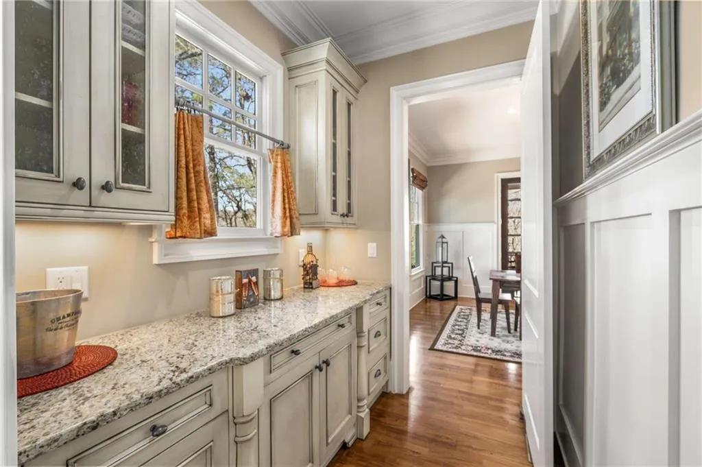 Bar featuring a wainscoted wall, ornamental molding, dark wood finished floors, and a decorative wall