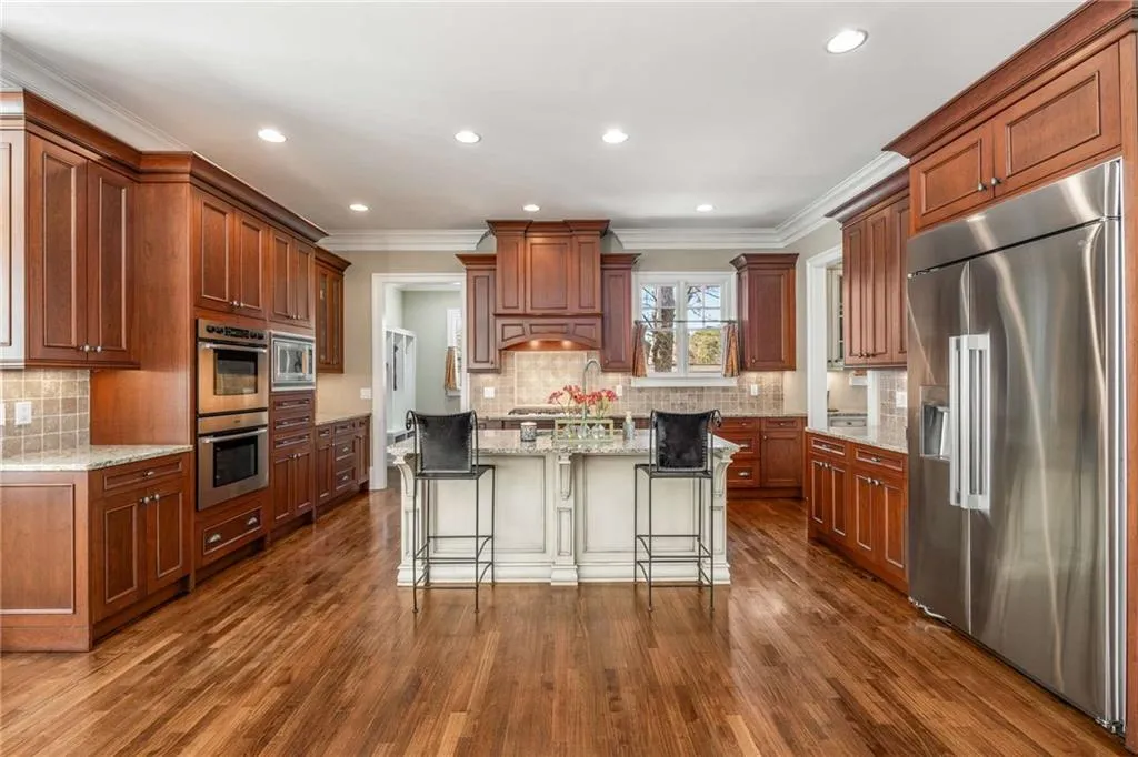 Kitchen with light stone counters, a breakfast bar, crown molding, appliances with stainless steel finishes, and dark wood-type flooring