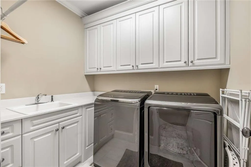 Washroom featuring cabinet space, tile patterned floors, independent washer and dryer, crown molding, and a sink
