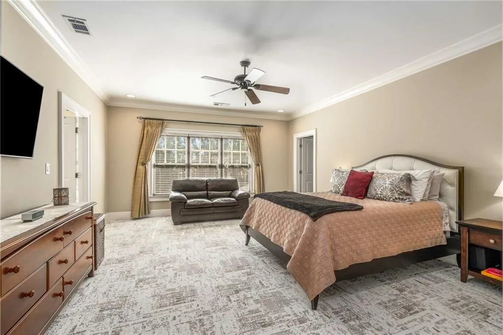 Bedroom featuring baseboards, ornamental molding, visible vents, and light colored carpet