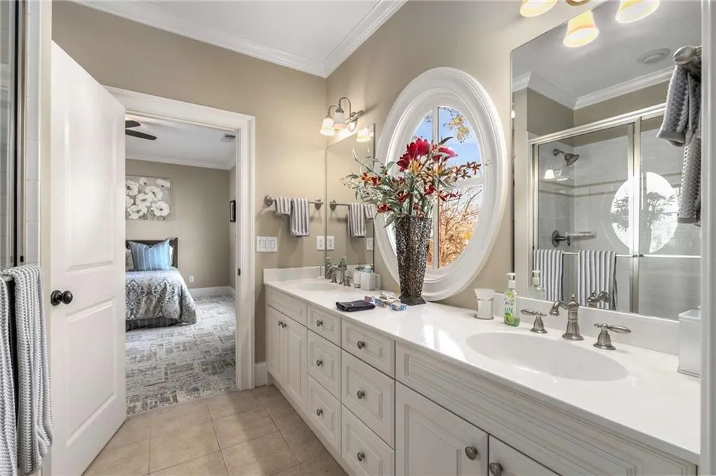 Ensuite bathroom featuring a sink, double vanity, a stall shower, ensuite bath, and crown molding