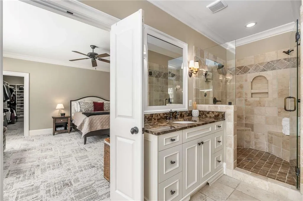 Ensuite bathroom with visible vents, crown molding, a shower stall, and vanity