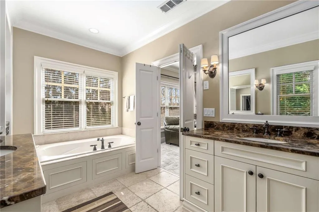 Bathroom with a garden tub, vanity, visible vents, and crown molding