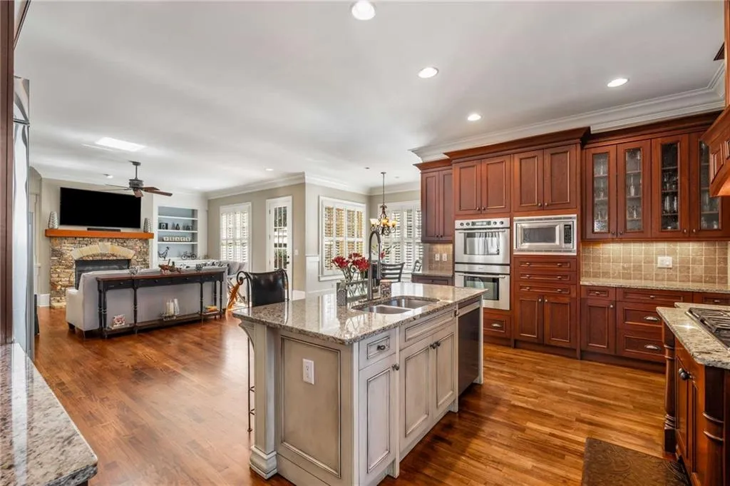Kitchen with dark wood finished floors, glass insert cabinets, stainless steel appliances, a fireplace, and a sink