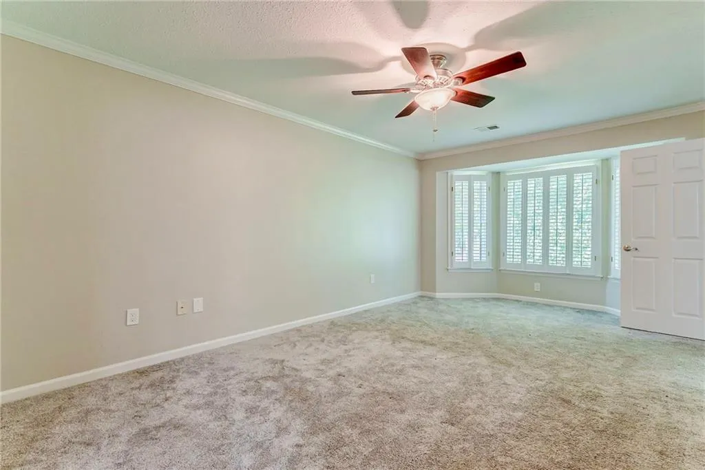 Carpeted spare room featuring crown molding, ceiling fan, and a textured ceiling