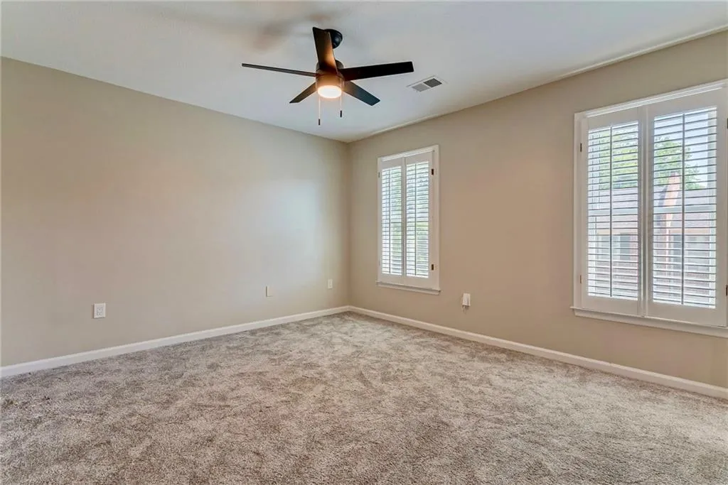 Carpeted spare room with baseboards and a ceiling fan