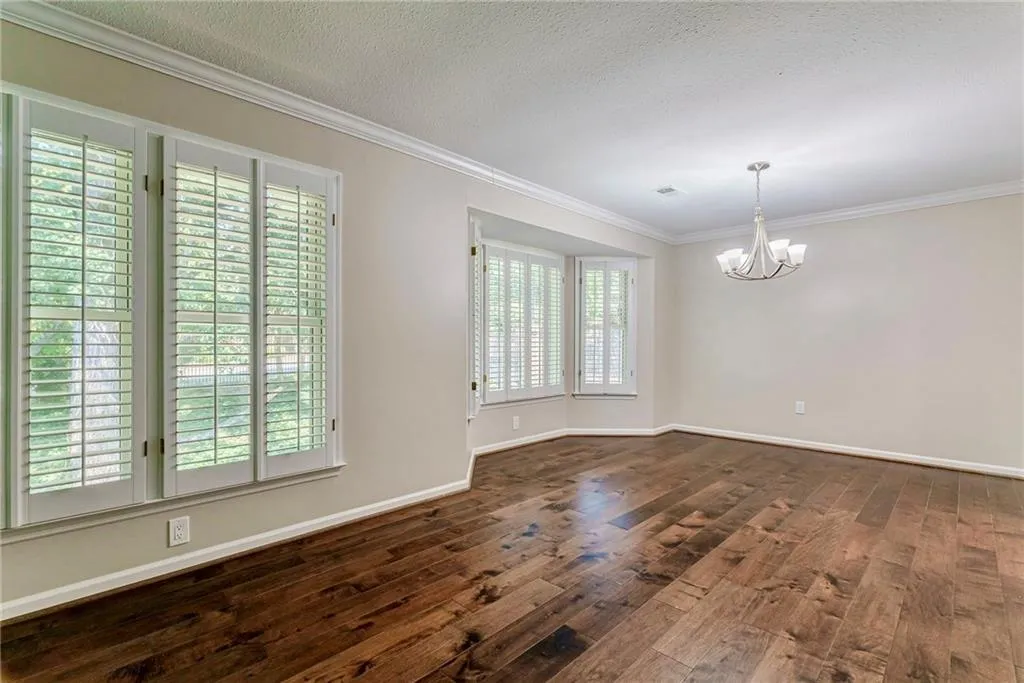 Spare room with crown molding, a chandelier, dark wood-style flooring, and a textured ceiling