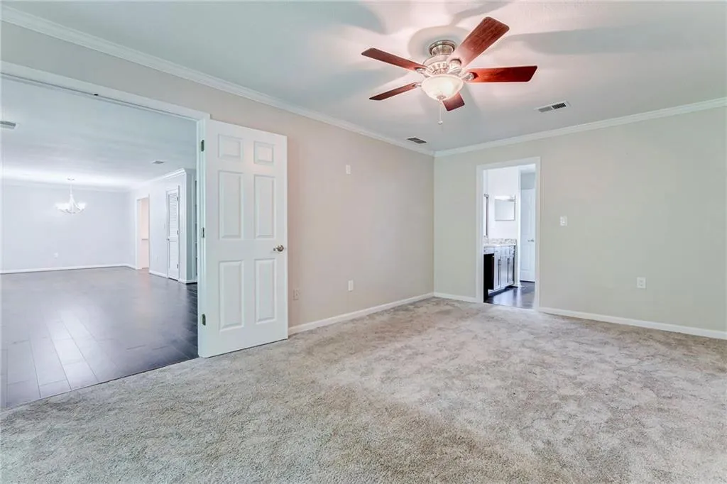 Unfurnished room featuring crown molding, carpet, a chandelier, and a ceiling fan