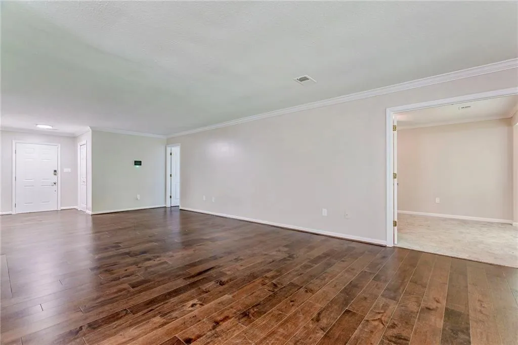 Unfurnished living room with ornamental molding and dark wood-style floors
