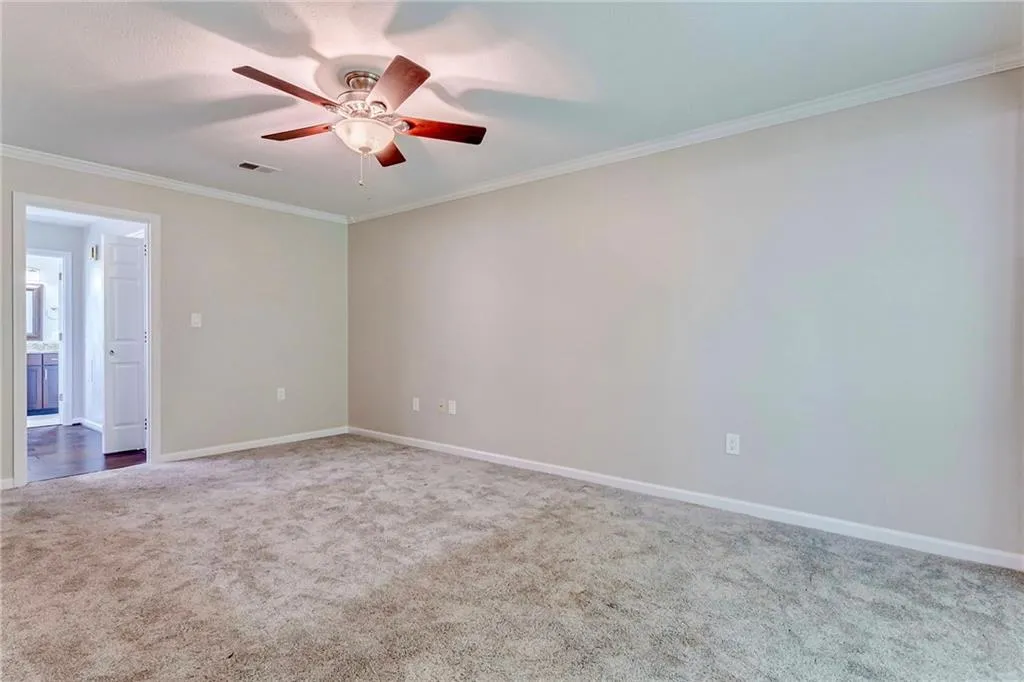 Carpeted empty room with crown molding and a ceiling fan