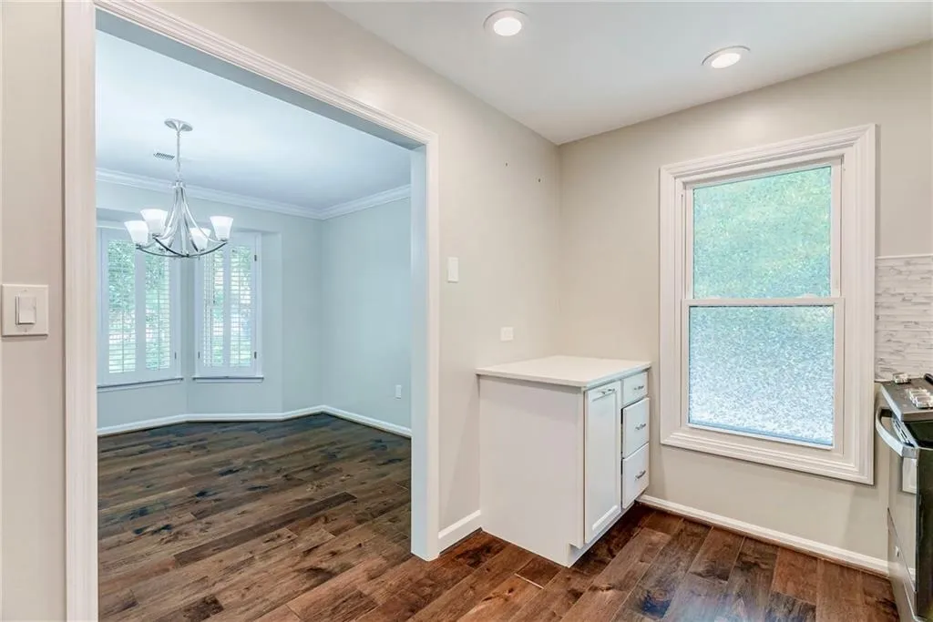 Kitchen with dark wood-type flooring, stainless steel range, a chandelier, recessed lighting, and white cabinets