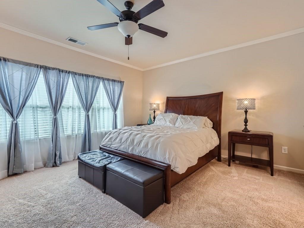 Bedroom with ornamental molding, light colored carpet, and ceiling fan