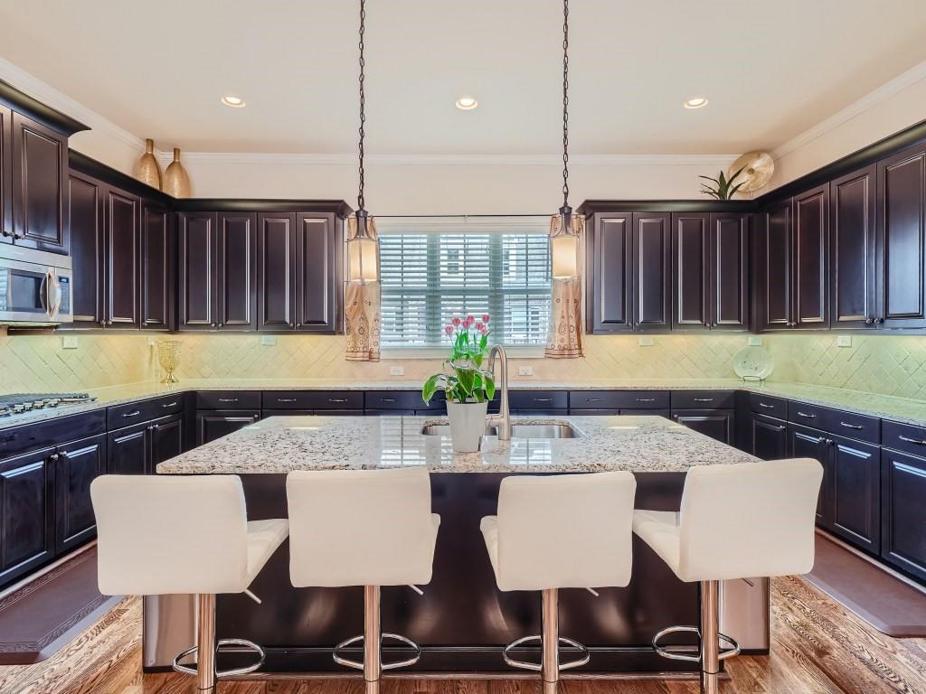 Kitchen with hardwood / wood-style flooring, tasteful backsplash, a kitchen bar, and decorative light fixtures