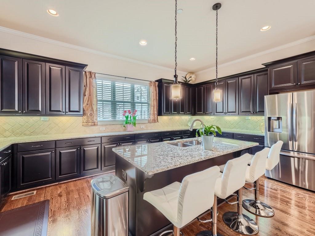Kitchen with a kitchen island with sink, light hardwood / wood-style floors, sink, pendant lighting, and stainless steel refrigerator with ice dispenser