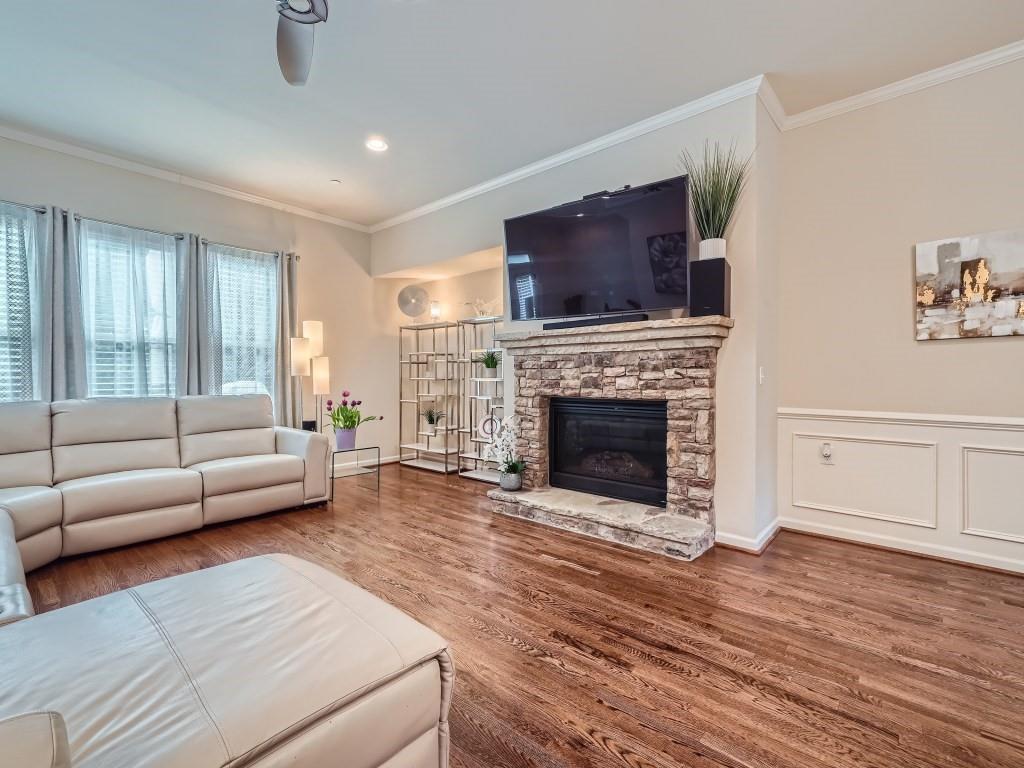 Living room with a fireplace, dark hardwood / wood-style flooring, ceiling fan, and crown molding
