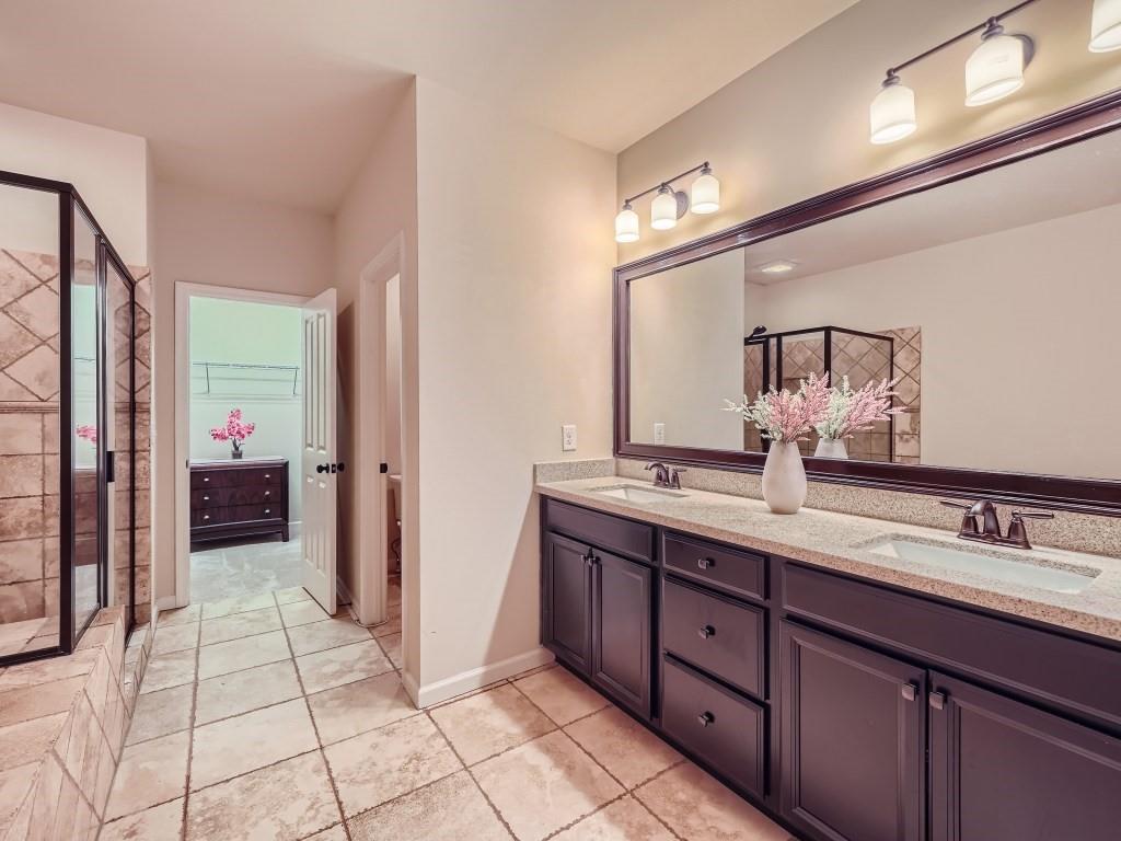Bathroom featuring walk in shower, double vanity, and tile floors