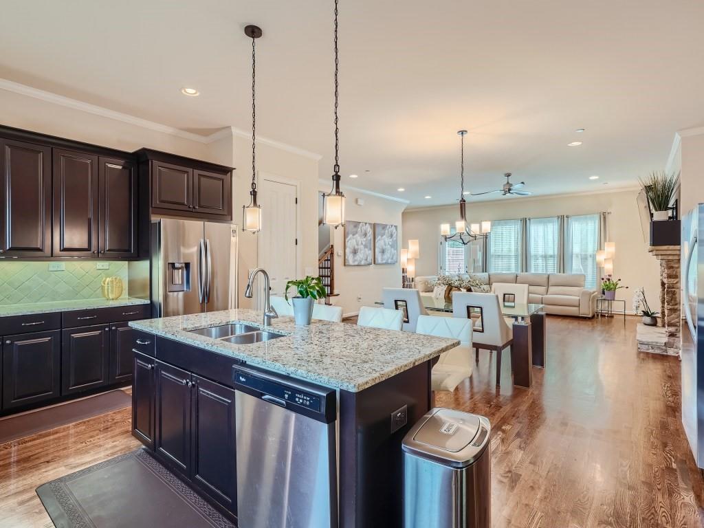 Kitchen featuring stainless steel appliances, a kitchen island with sink, light hardwood / wood-style floors, sink, and ceiling fan with notable chandelier