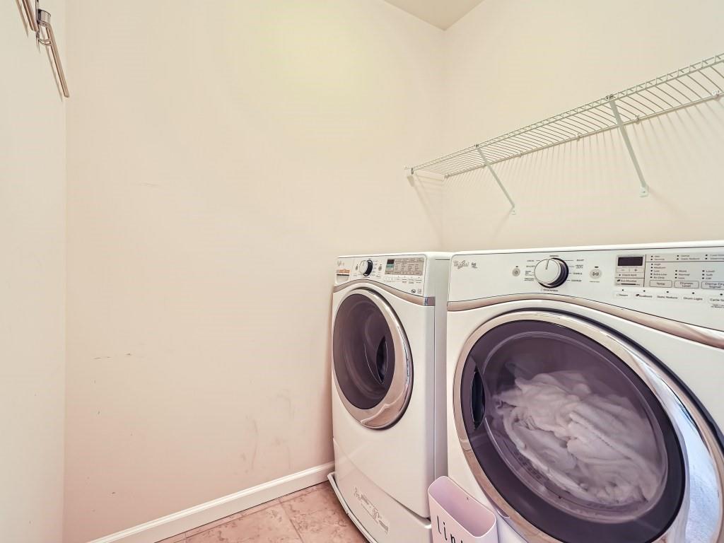 Clothes washing area featuring light tile flooring and separate washer and dryer