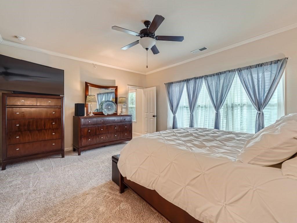 Bedroom with ornamental molding, light colored carpet, and ceiling fan
