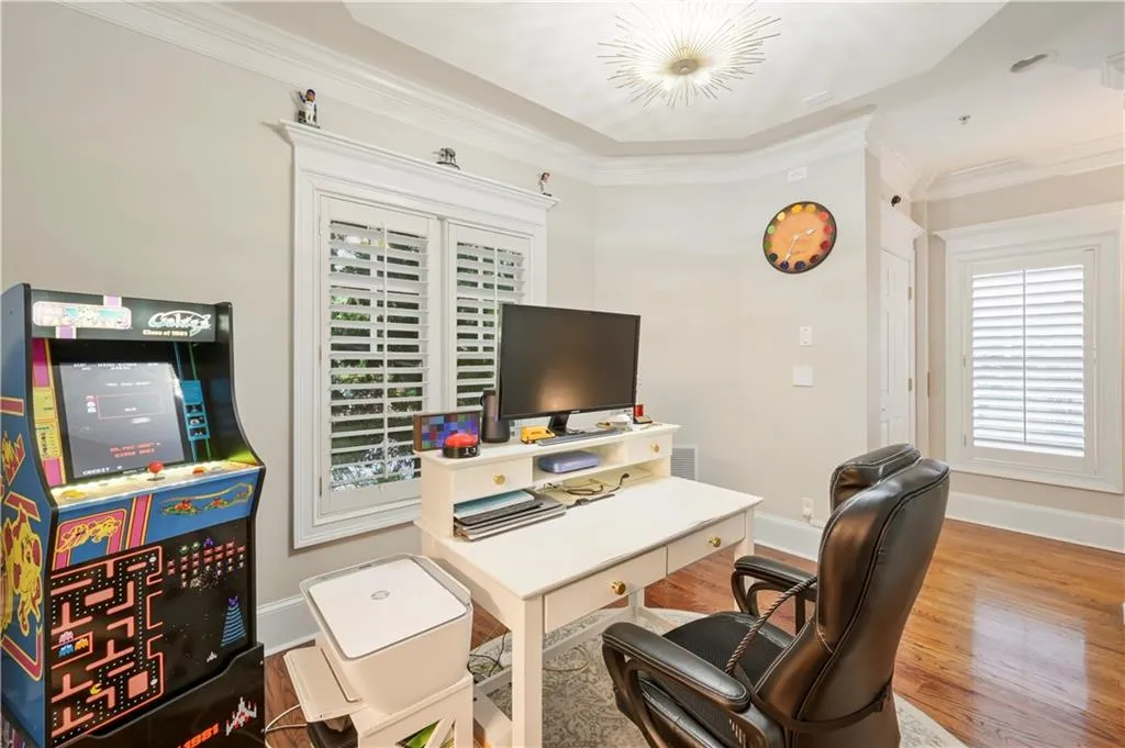 Room featuring crown molding, wood-finish flooring, plantation shutters, and a starburst-style ceiling light fixture