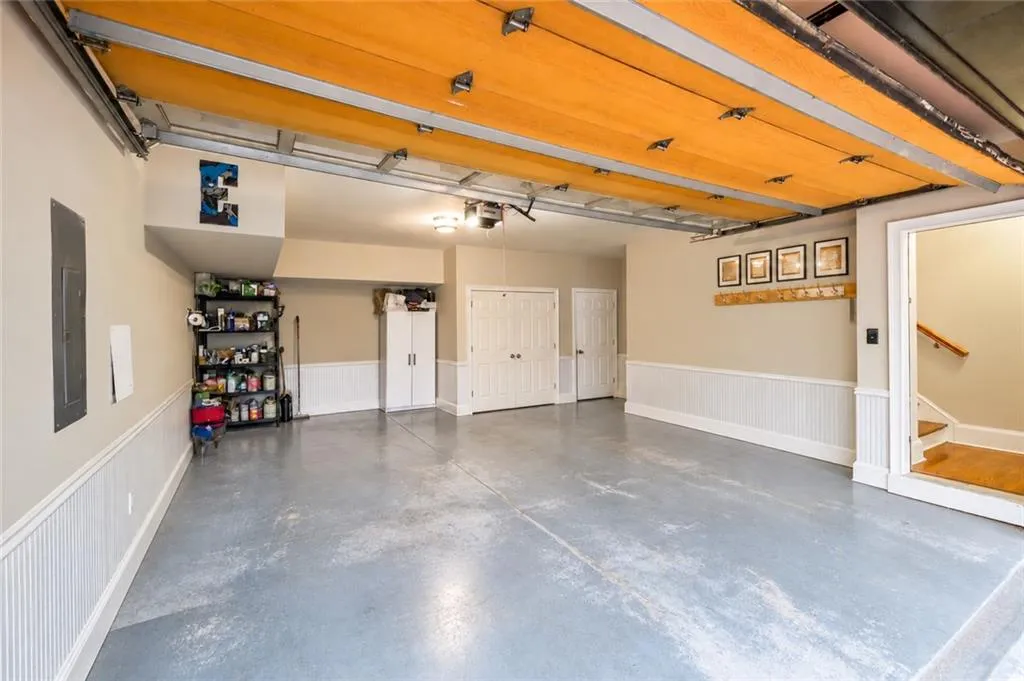 Multi-car garage featuring beadboard wainscoting, an epoxy-coated floor, and built-in storage cabinetry