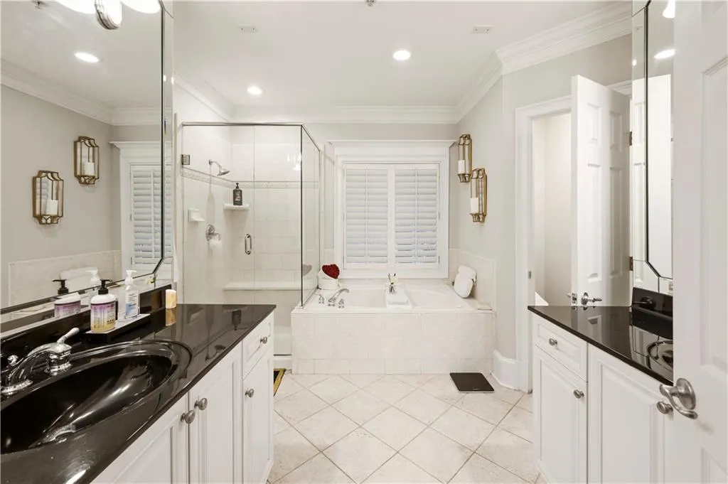 Bathroom featuring white cabinetry, dark stone countertops, an integrated glass-enclosed shower, a deep soaking tub, and tile flooring