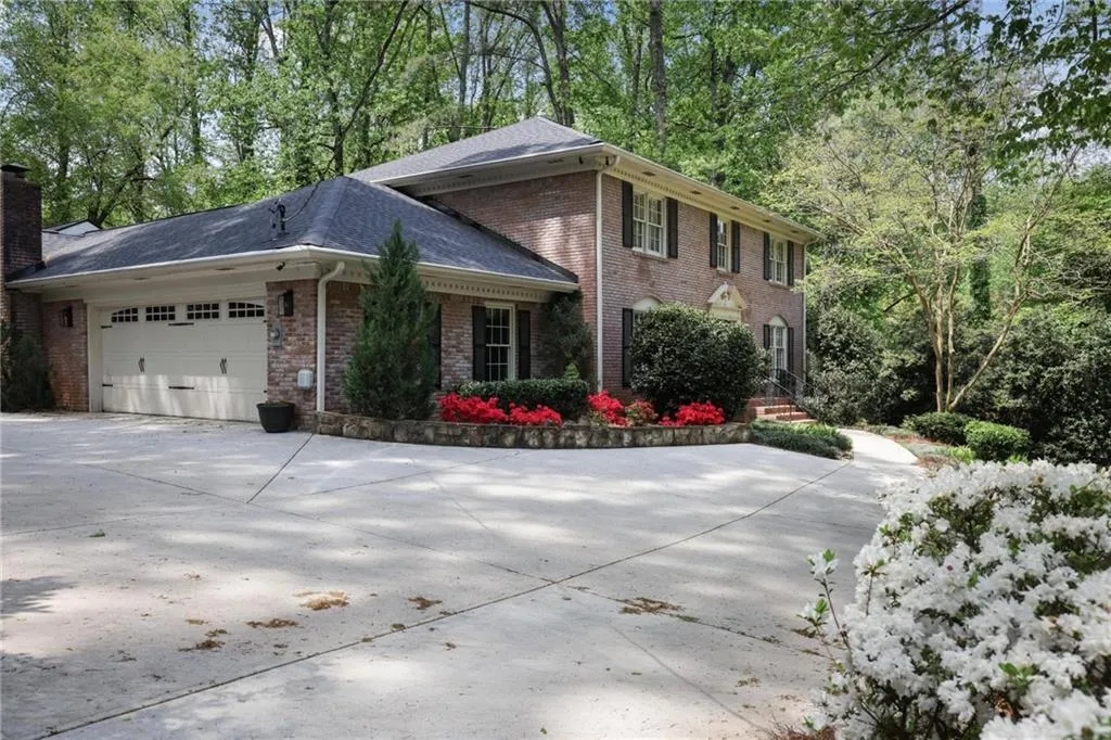 View of side of home featuring a garage, brick siding, concrete driveway, and a chimney