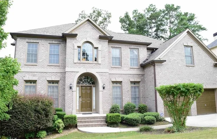 Brick exterior with arched entry, complementing double garage doors, and arched window details