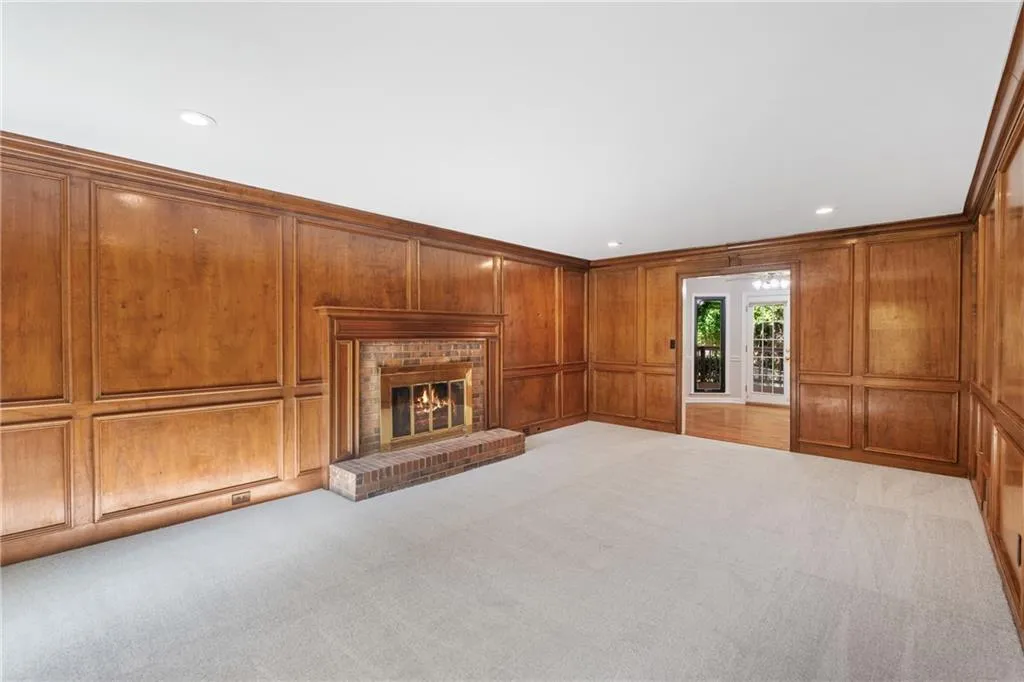 Unfurnished living room with wood walls, a fireplace, light colored carpet, and crown molding