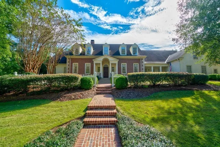 Brick facade colonial residence with multiple dormer windows, a covered front entry, and a brick pathway