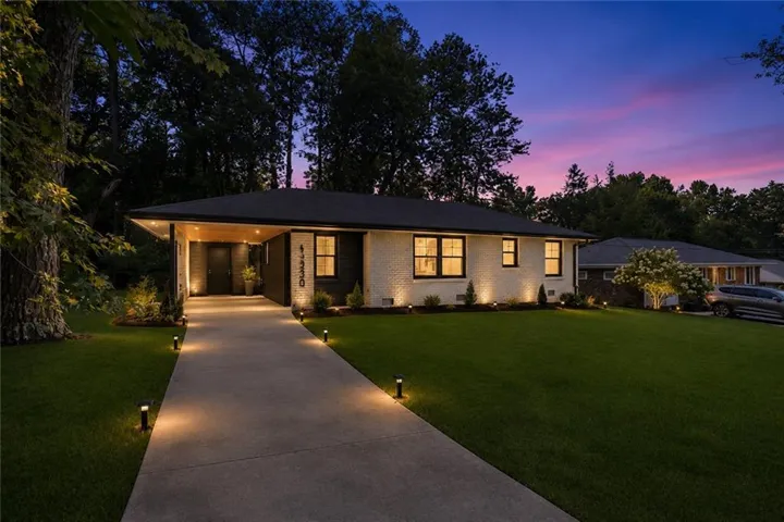 Contemporary ranch-style residence featuring a white brick and dark-paneled exterior