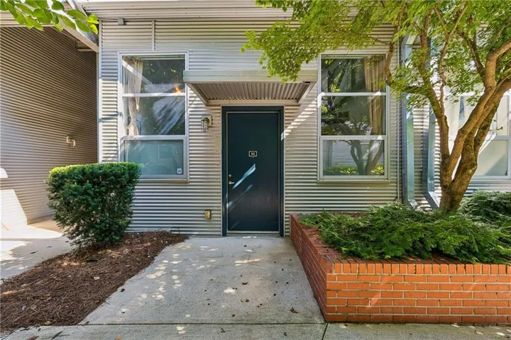 Corrugated metal exterior featuring a dark entry door with transom and side-by-side windows