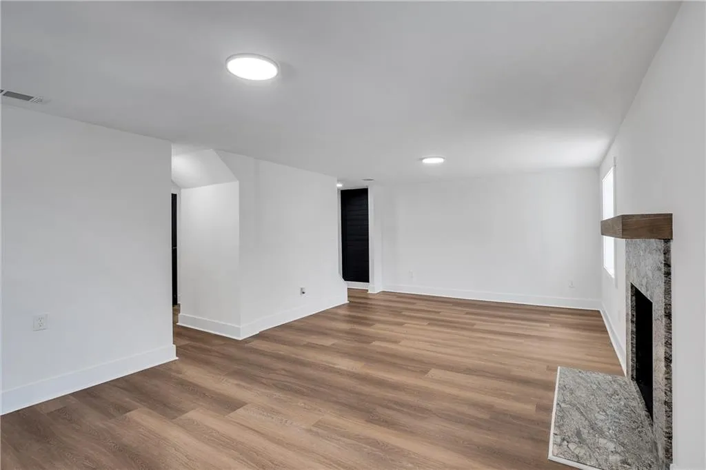 Basement with a fireplace with flush hearth, wood finished floors, visible vents, and baseboards