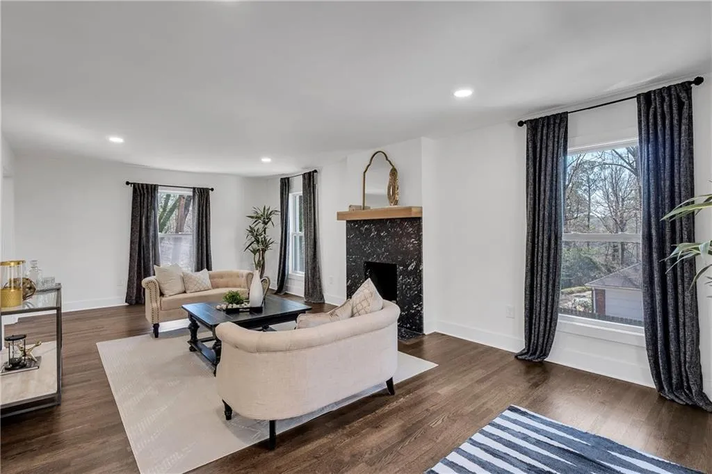 Living room with a wealth of natural light, baseboards, dark wood-type flooring, and a tiled fireplace