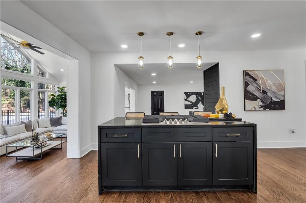 Kitchen with dark wood-type flooring, dark countertops, baseboards, ceiling fan, and hanging light fixtures