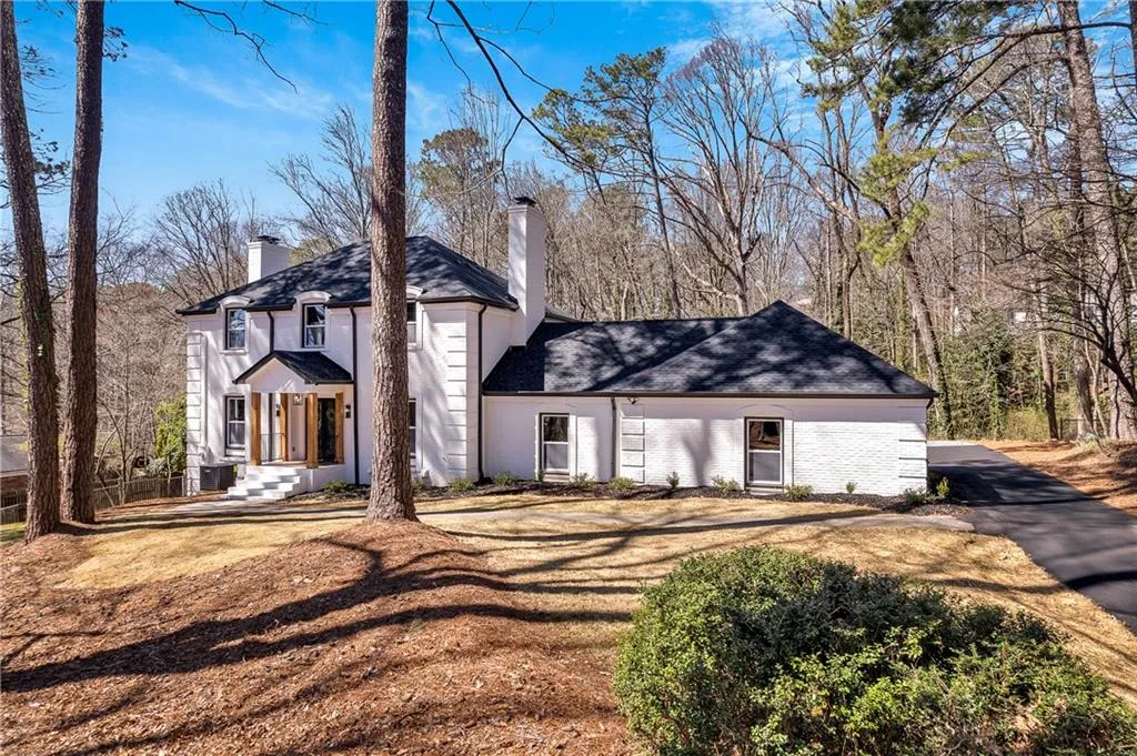 View of front facade featuring central air condition unit, brick siding, and a chimney