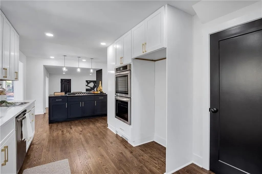 Kitchen with hanging light fixtures, white cabinets, appliances with stainless steel finishes, and dark wood-style flooring