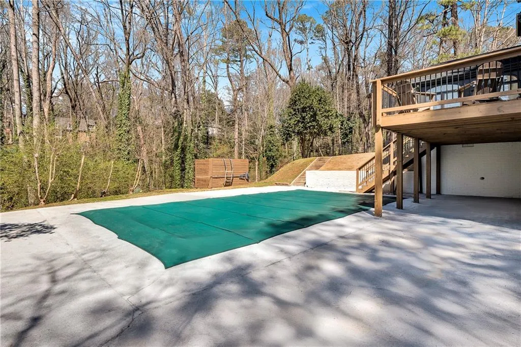 View of pool featuring stairway, a forest view, and a wooden deck
