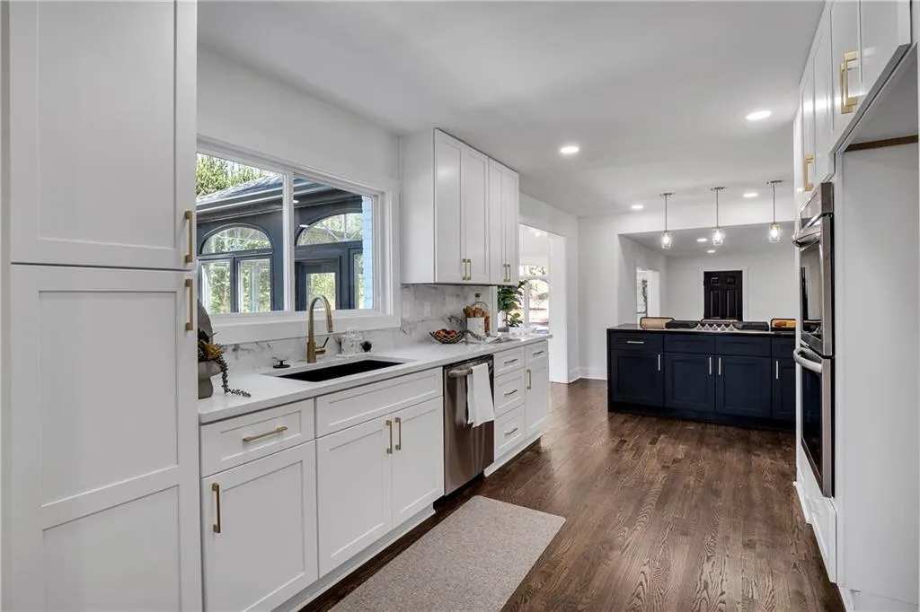 Kitchen featuring tasteful backsplash, a sink, appliances with stainless steel finishes, white cabinets, and dark wood-style flooring