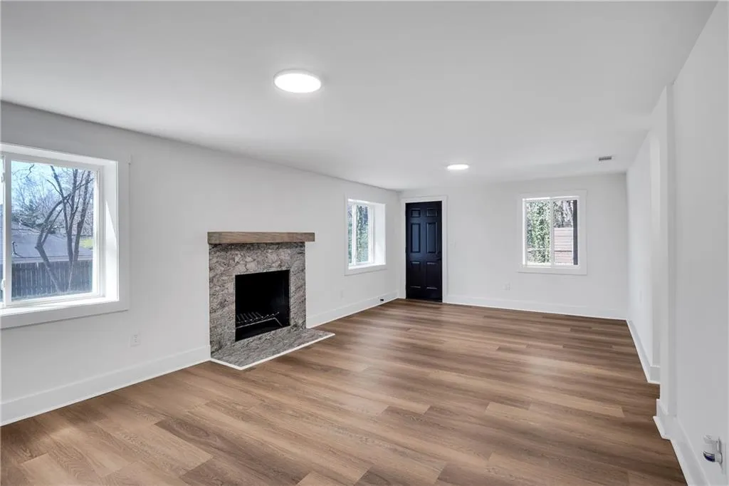 Unfurnished living room with a premium fireplace, baseboards, and wood finished floors