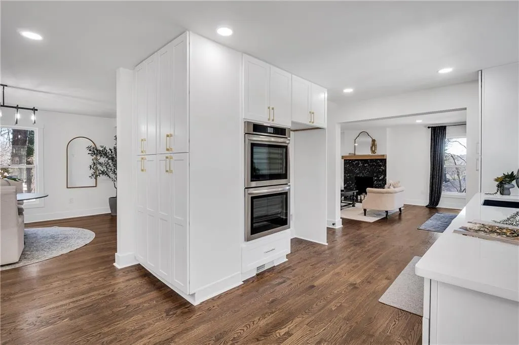 Kitchen with dark wood finished floors, stainless steel double oven, recessed lighting, white cabinets, and light countertops