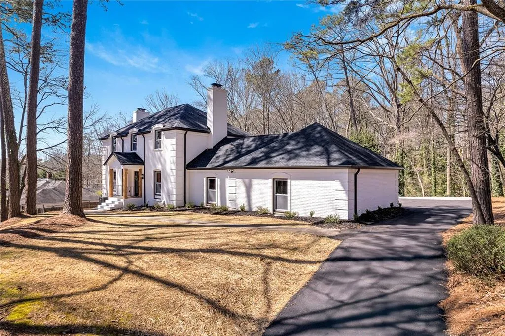 View of front facade with a front yard, brick siding, and a chimney