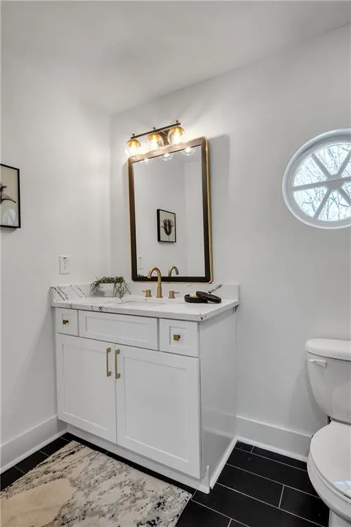 Bathroom featuring vanity, toilet, and baseboards