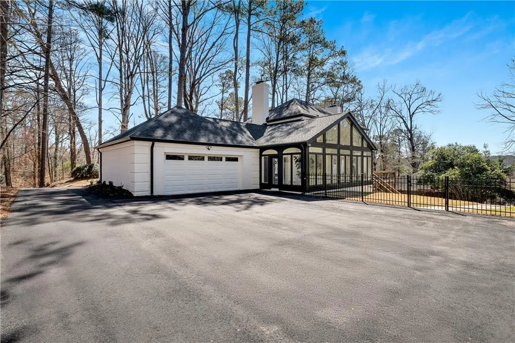 View of property exterior with fence, roof with shingles, a chimney, a garage, and driveway