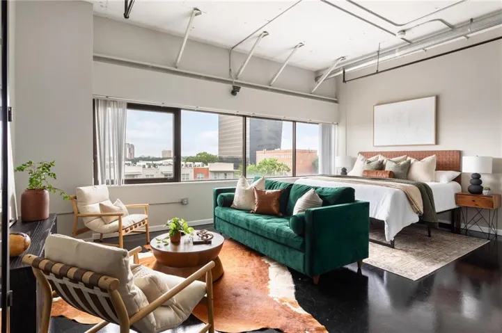Polished dark flooring, exposed ceiling conduits, expansive window-lined wall, and light-toned walls